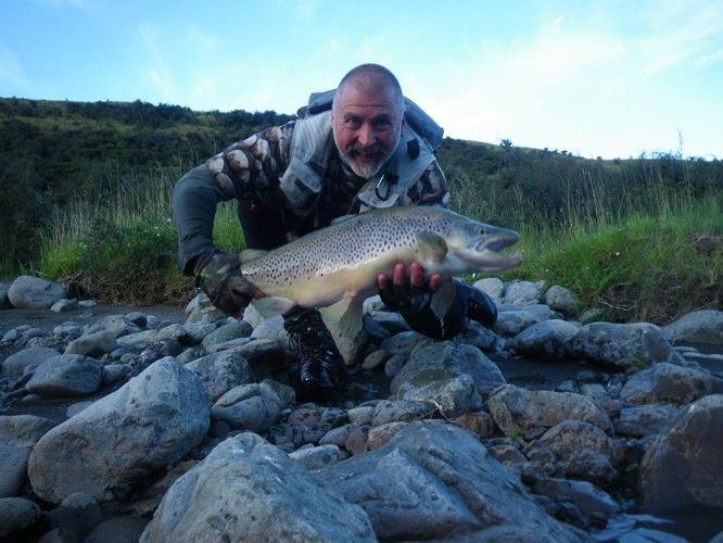 Angler holding a trout after a guided fishing trip in New Zealand